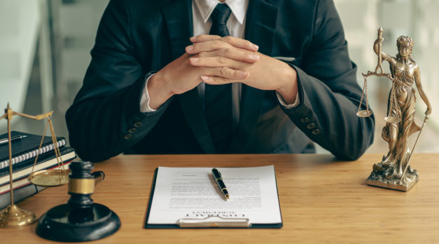 Concepts of justice and lawyers discuss contract paperwork with brass scales on a table with a judge's hammer placed in front of lawyers in the office. Legal, advice, justice, and conceptual services.