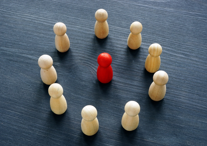 Circle from wooden figures and red figure. Discrimination or harassment concept.