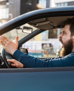 Aggressive bearded Caucasian man yelling and shouting in traffic, road rage concept