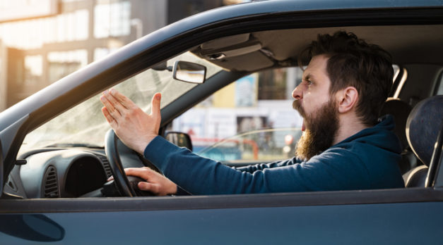 Aggressive bearded Caucasian man yelling and shouting in traffic, road rage concept