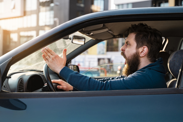 Aggressive bearded Caucasian man yelling and shouting in traffic, road rage concept