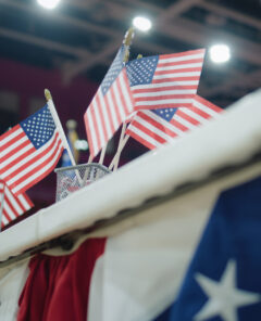 Elections in the United States of America. Close up of table for voting registration with American flags standing at polling place. Presidential race and election coverage. Civic duty and patriotism.