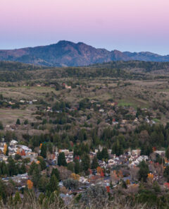 Aerial view of the town of Santa Rosa, California, nestled in a valley at sunset beneath a mountain. Rural community in Sonoma County wine country at dusk.