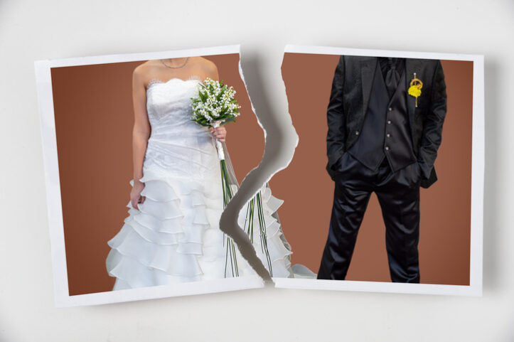 Divorce concept. Torn photograph of a couple at their wedding with red background