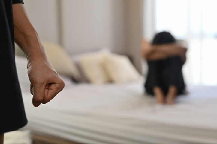 Selective focus on the fist male with crying man sits on a bed as the background, Violence, Love and relationships, Gay couple, sexual harassment concept.