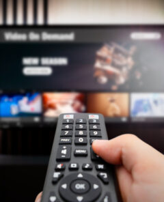 VOD service screen. Man watching TV with remote control in hand.